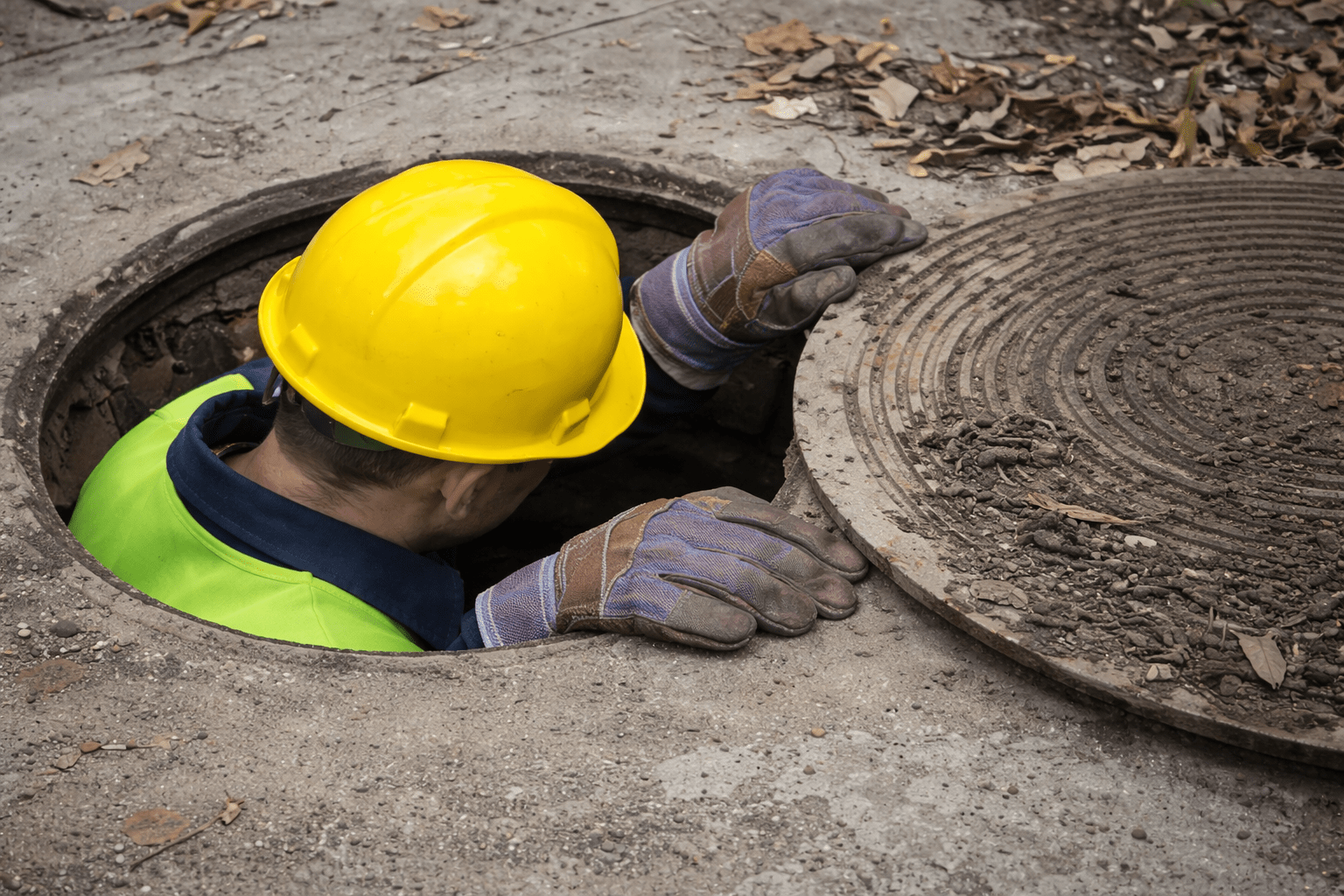 Construction worker emerging from manhole